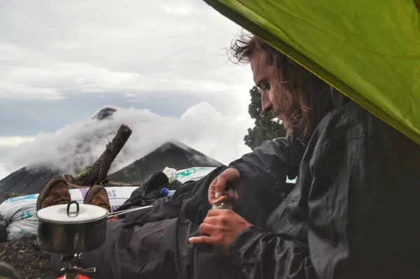 camper Settled and making a cup of tea while camping on slope of acatenango with a view of volcan del fuego
