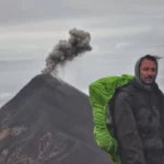 hiker On the summit of Acatenango with Volcán del Fuego in the background