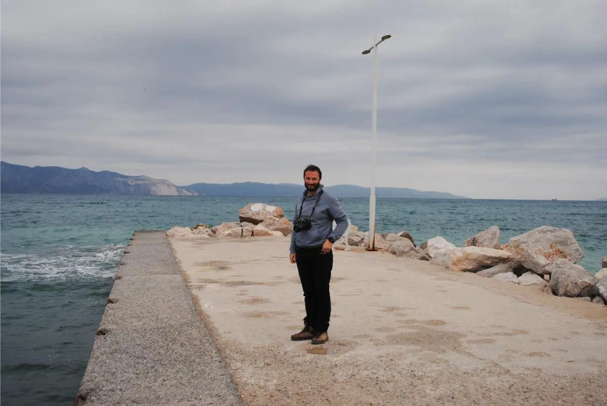 guy with a camera at the fishing port of asminio village in north evia