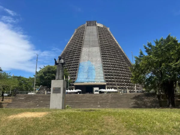 Rio de Janeiro’s Catedral Metropolitana, a towering modernist structure with a conical shape, rises behind lush greenery and contrasts with the colonial textures of nearby Lapa, adding architectural diversity to the area.
