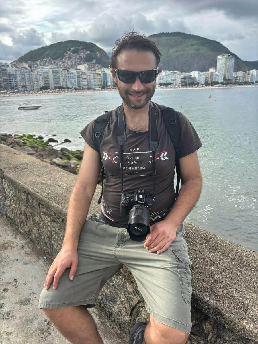 traveler standing near the rocks at Fort Copacabana with copacabana beach in the background and the Atlantic Ocean stretching out beyond, capturing the scenic southern tip of Rio.