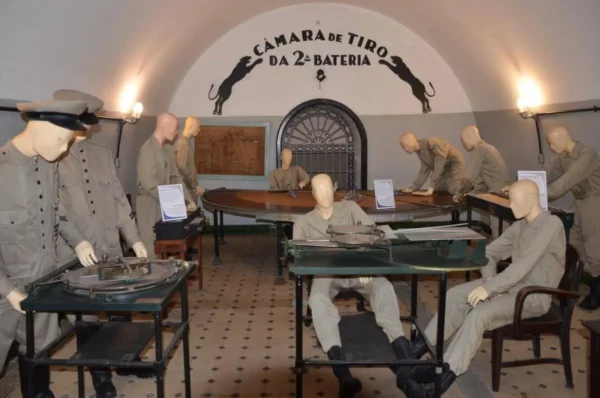 Military exhibit inside Fort Copacabana’s turret bunker featuring mannequins dressed as soldiers operating artillery, depicting how Brazilian forces managed the space during its active use.