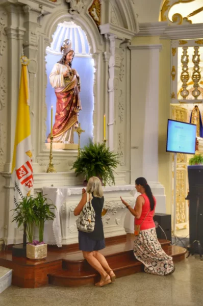 Women praying below tall jesus statued inside the metropolitan cathedral of florianopolis