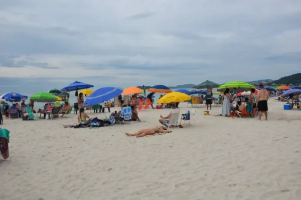 bathers with colorful parasols at jurere beach in cloudy weather