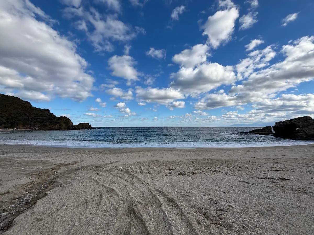 Wide view of the northern cove of kalamos beach under blue sky with scattered cumulus clouds in evia greeece