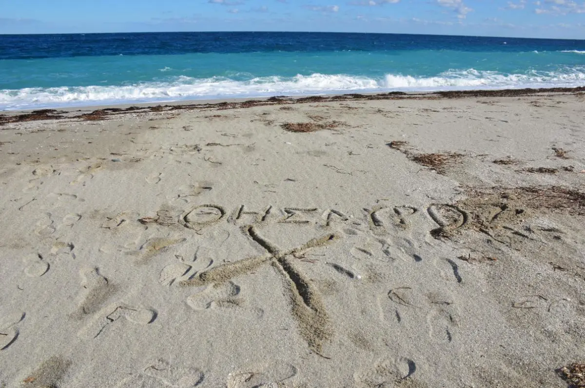 an X and θησαυρός (Greek for treasure) carved in sand at korasida beach on east evia island