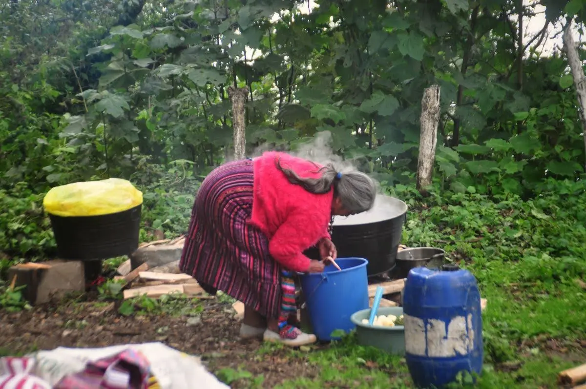 old mam maya woman cooking in big cauldron in the forest