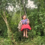 little mam maya girl on a rope swing at the shore of laguna chicabal