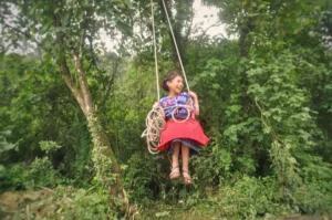 little mam maya girl on a rope swing at the shore of laguna chicabal