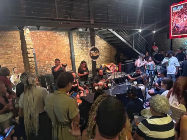 A lively samba band plays on stage inside a packed Lapa venue in Rio de Janeiro, as dancers crowd the floor and cheer, immersed in Brazil’s most iconic musical tradition.