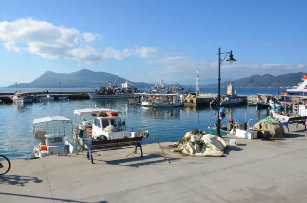 Fishing boats and nets at Edipsos harbor with mountains across the bay in northern Evia, Greece