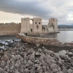 Panoramic coastal view of Methoni in Messinia, Greece, with the Ionian Sea, rocky shoreline, and the medieval Methoni Castle extending into the water.