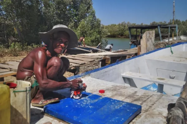 Vieil homme malgache lavant un linge sur une pirogue