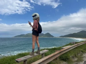 girl wearing a helmet Enjoying a panoramic view of Armação Beach in florianopolis during a bike ride break