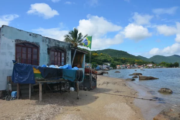 Casas de praia e bandeira do Brasil ao longo da costa de Ribeirão da Ilha