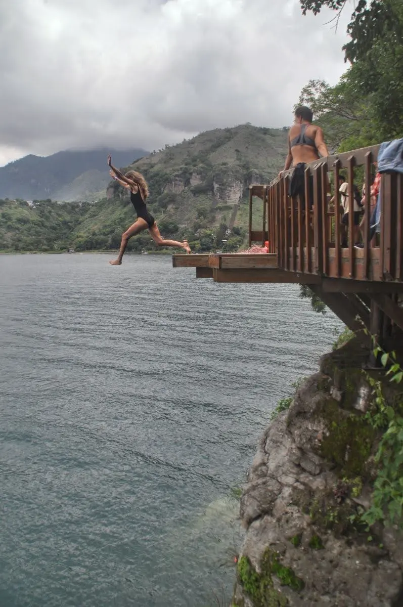 girl stepping off cliff jumping platform in san marcos la laguna, lake atitlan