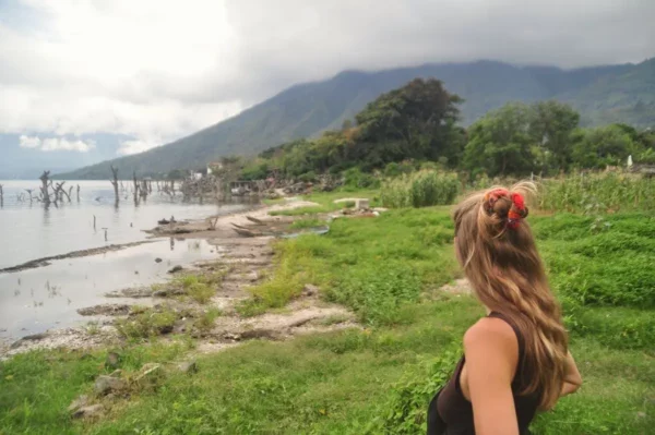 Woman looking out over the shoreline of Lake Atitlán with mountains and clouds in the background