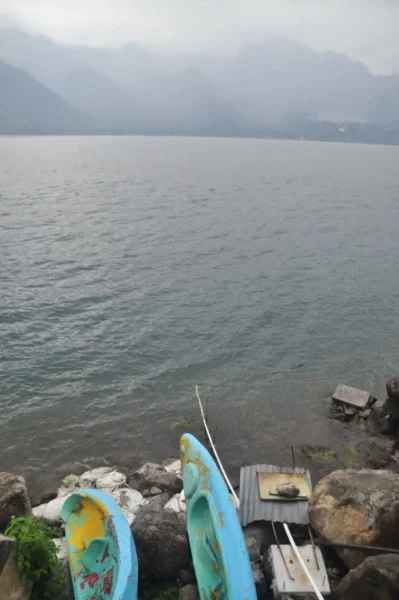 two blue kayaks lying on rocky shore of lake atitlan at hotel san antonio in san pedro la laguna