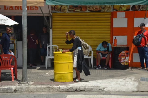 Usuária idosa tocando um barril metálico amarelo