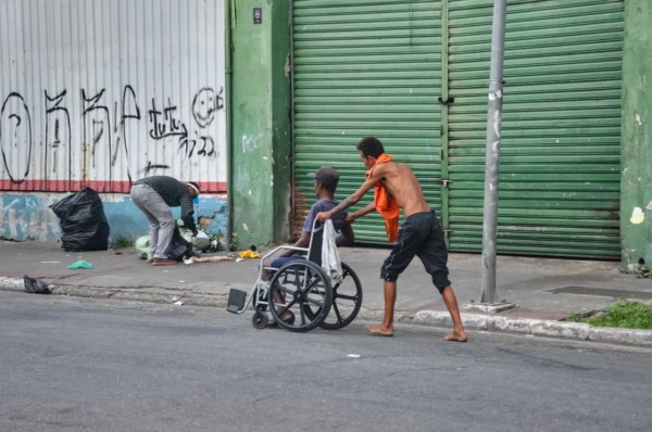 Usuário empurrando seu amigo cadeirante pelas ruas da Cracolândia