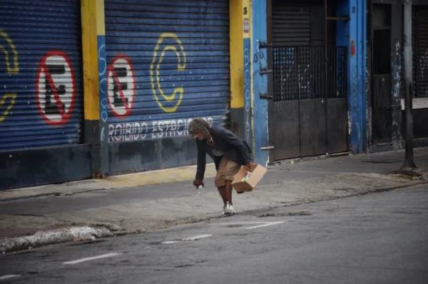 Usuário idoso remexendo o lixo em uma rua da Cracolândia