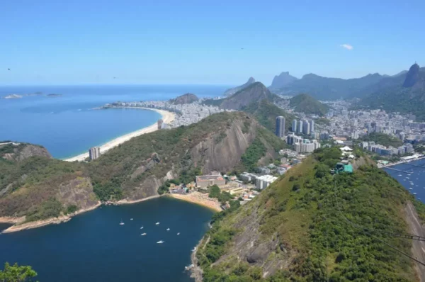 Panoramic view from the summit of Sugarloaf Mountain, showing Rio de Janeiro’s coastline, blue ocean, and green hills under a bright sky