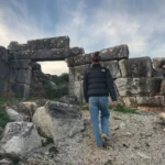 girl Walking past the gate of ancient Dystos on evia island, greece
