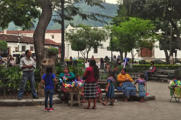 Vendors and families gathered in Antigua’s main square, with Maya women in traditional clothing and trees framing the plaza