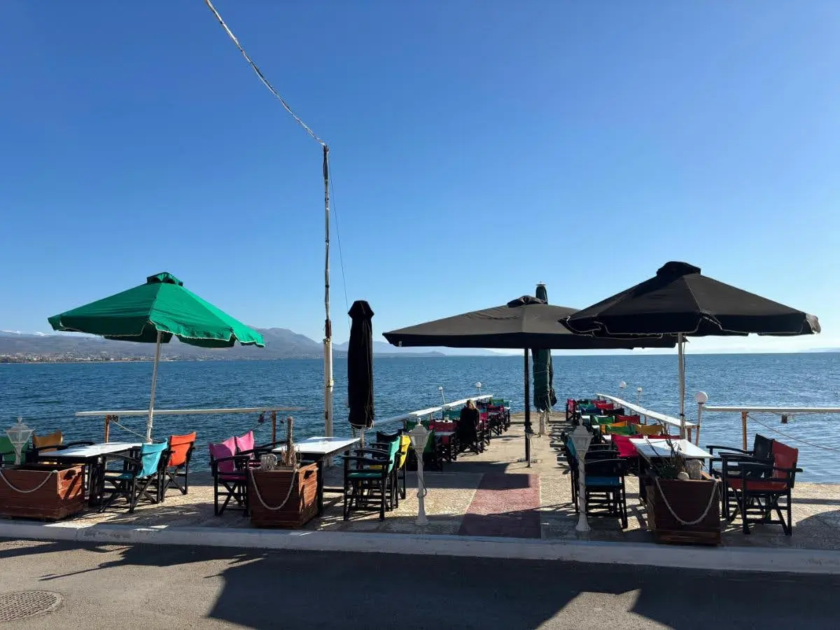 pretty cafe with greek and black umbrellas on little pier in the village of avlida, evia island