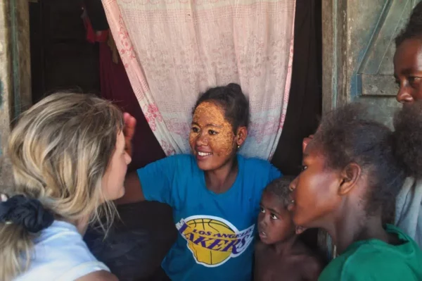Femme malgache appliquant un masque traditionnel sur le visage d’une Européenne