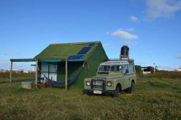 green hovel with hammock and green jeep in open grass field in cabo polonio