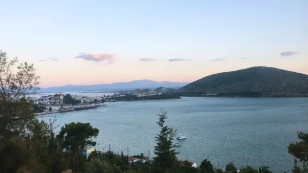 Tranquil waters of Chalkis in Euboea, Greece, with distant hills and a pastel sky reflecting the soft evening light.