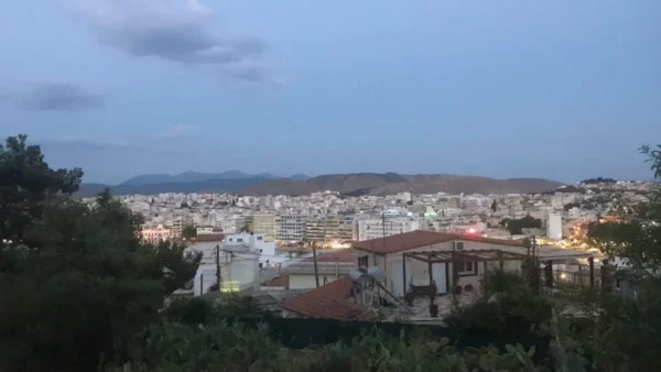 A panoramic view of Chalkis at dusk, showcasing lit buildings and distant mountains under a twilight sky in Euboea, Greece.