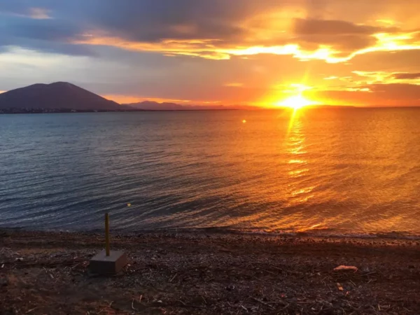 Stunning sunset over the tranquil waters of Chalkis, Euboea, highlighting golden hues reflecting on the sea.