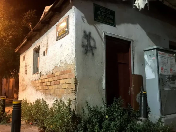 Weathered building with peeling paint and graffiti, surrounded by greenery in Chalkis, Euboea, Greece.