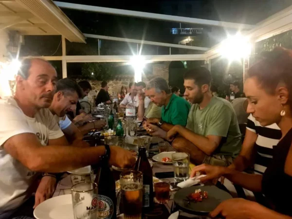 Dining scene with people enjoying a meal at a restaurant in Chalkis, Euboea, Greece, featuring plates of food and drinks.