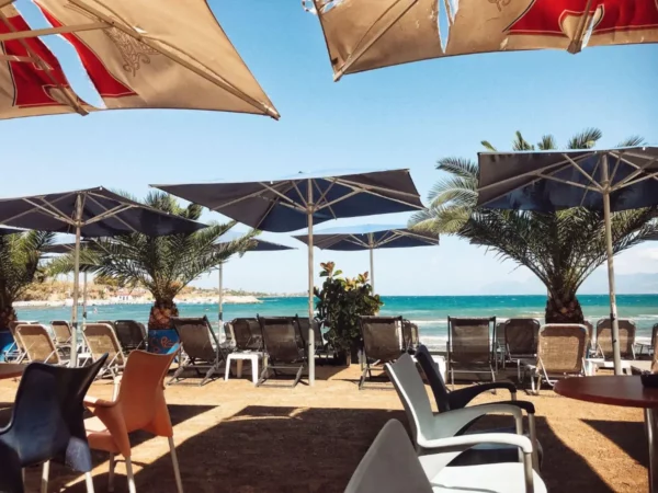 Beachside umbrellas and lounge chairs create a relaxed atmosphere overlooking the tranquil waters of Chalkis, Euboea, Greece.