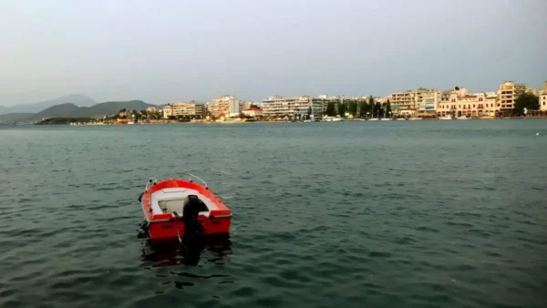 Chalkis showcases a quiet harbor with a red boat floating in calm waters, framed by the coastal town's modern buildings.