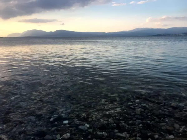Tranquil waters shimmer in the evening light, reflecting hues of blue and gold near Chalkis, Euboea, Greece.