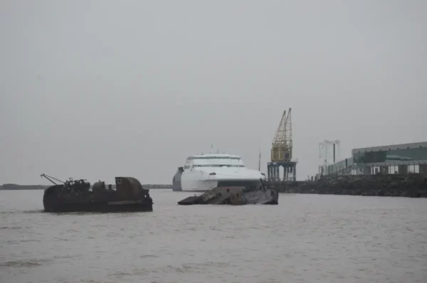 The ferry at the port of Colonia behind a rusted sunken ship in the fog