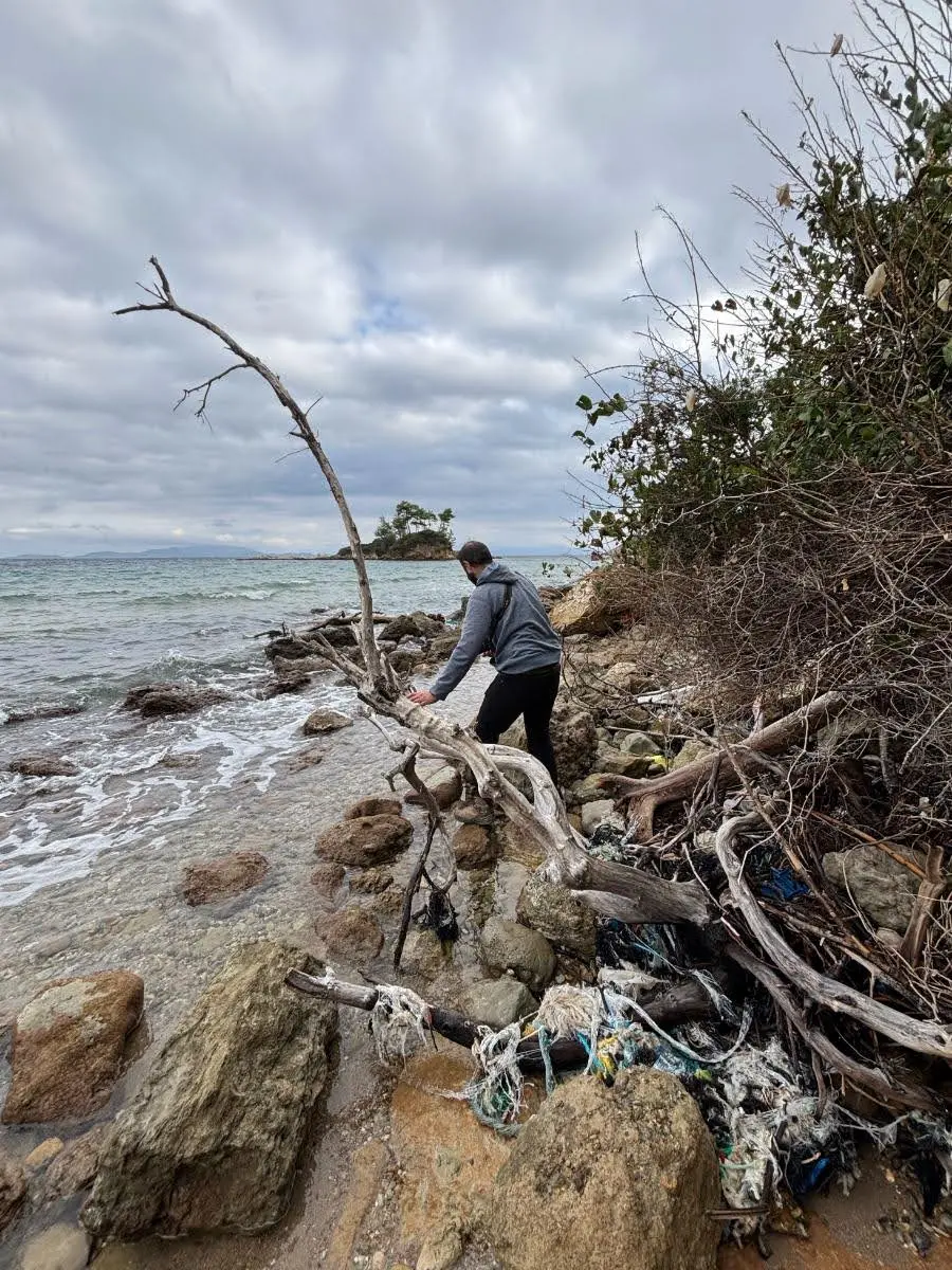 man jumping over big pieces of driftwood on coast of north evia island 
