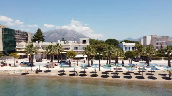 Palm-lined beach and waterfront in Eretria, Euboea, Greece, with Mount Olympus in the background.