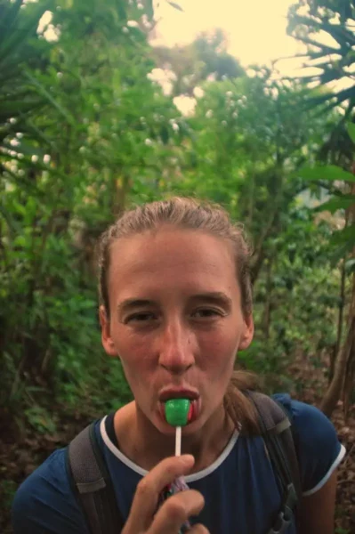 A traveler enjoys a green lollipop while surrounded by lush greenery near Lake Atitlán, Guatemala.