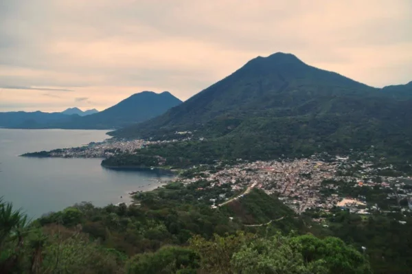 Lush green hills and the calm waters of Lake Atitlán surrounded by mountains set a serene backdrop in Guatemala.