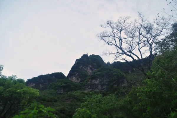Majestic peak of Indian Nose rises above lush greenery near Lake Atitlán, Guatemala, under a cloudy sky.