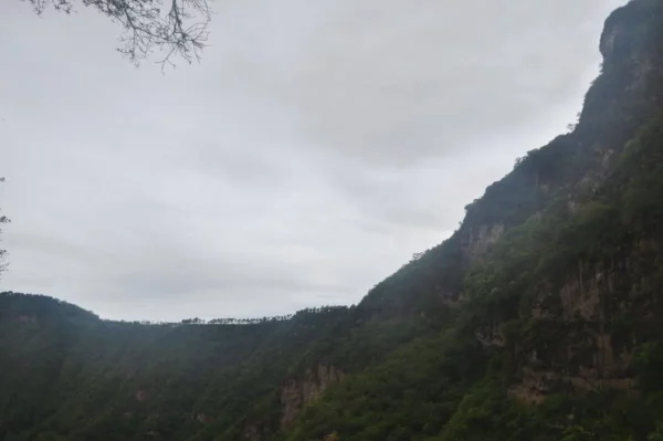 Cloudy skies loom over the lush green hills and rocky cliffs framing Indian Nose at Lake Atitlán, Guatemala.