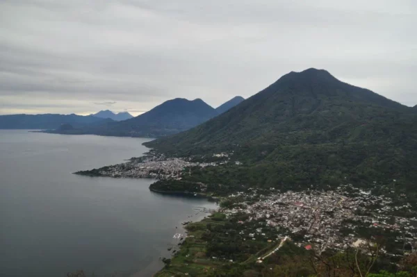 Indian Nose overlooks Lake Atitlán in Guatemala, showcasing vibrant landscapes with mountains and serene waters under a cloudy sky.