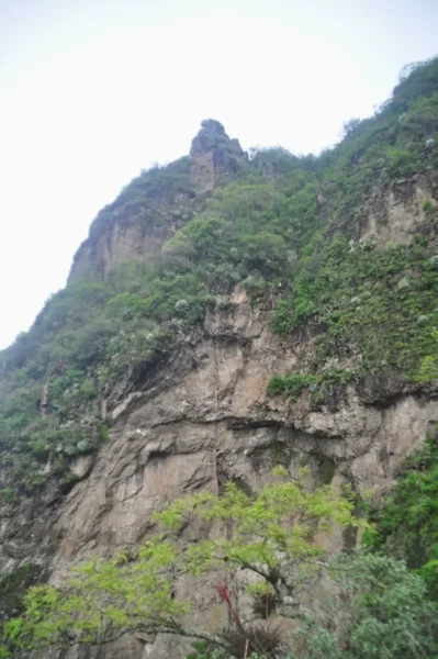 Majestic cliffs adorned with lush greenery rise sharply above Lake Atitlán, encapsulating the serene beauty of Guatemala.