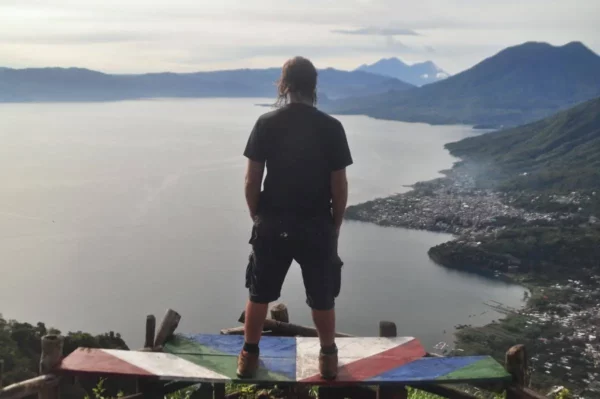 Person standing on a viewpoint above Lake Atitlán, looking toward the surrounding volcanoes