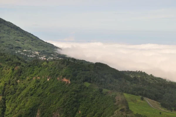 Lush green hills and misty clouds envelop the landscape near Lake Atitlán, Guatemala, showcasing the region's natural beauty.